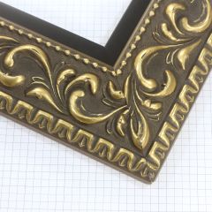 A large, reverse curve profile frame with an intricate leaf design bordered by a geometric outer edge and beaded inner lip.  A dark, matte gold-brown base with gold foil patina for added depth on the topmost points of the design. Strong, solid wood construction.

3.25 " witdth: ideal for large and oversize (extra large) images.